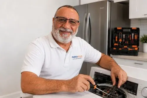 Parrahills technician repairing a washing machine in a Sydney home, fridge in background